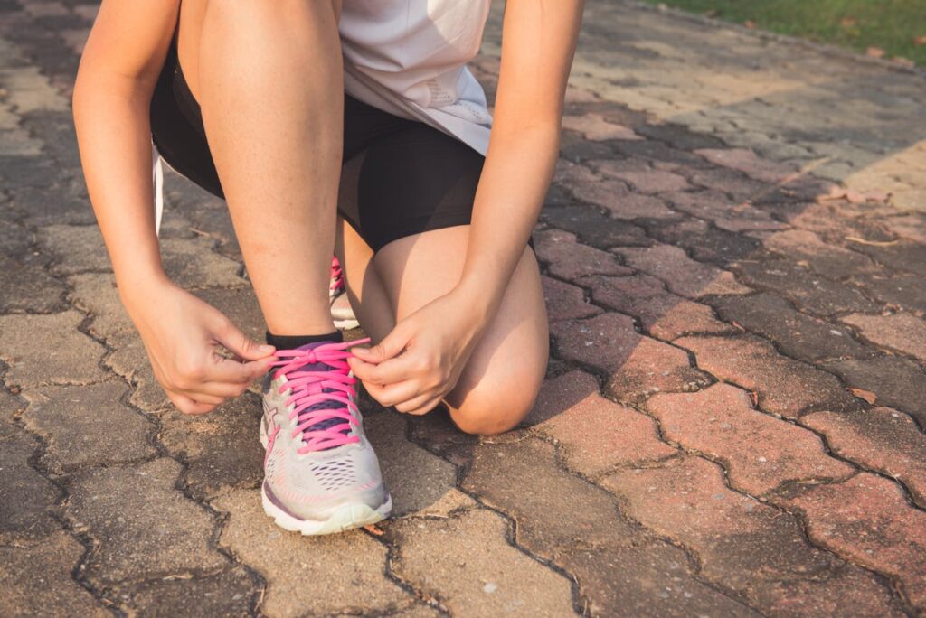 Woman Lacing Up Her Gray and Pink Nike Low-top Athletic Shoe // Healthier Veterans Today