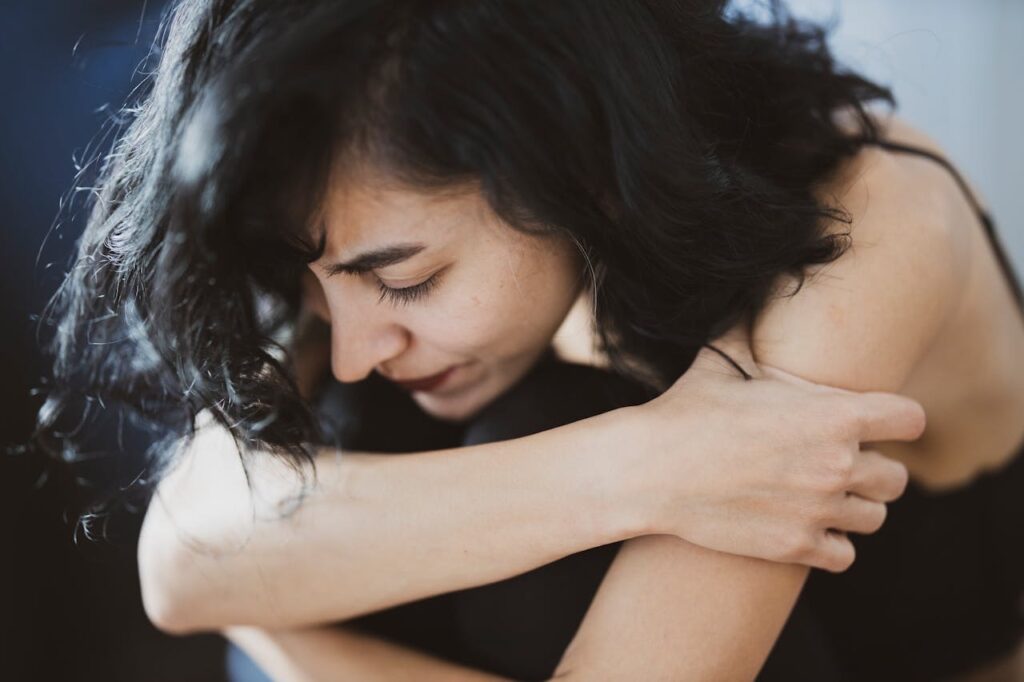 Woman bearing black, folding her arms and looking down // Healthier Veterans Today