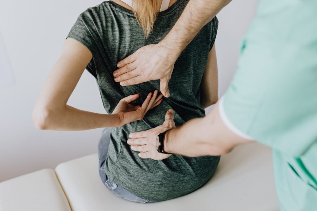 Doctor inspecting a woman's back that is paining while on table // Healthier Veterans Today