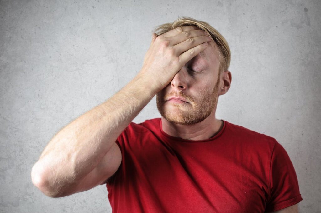 Man holding his head, wearing a red shirt // Healthier Veterans Today