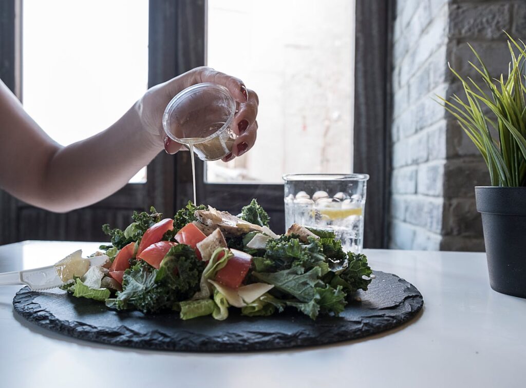 Person Pouring Dip on Vegetable Salad // Healthier Veterans Today